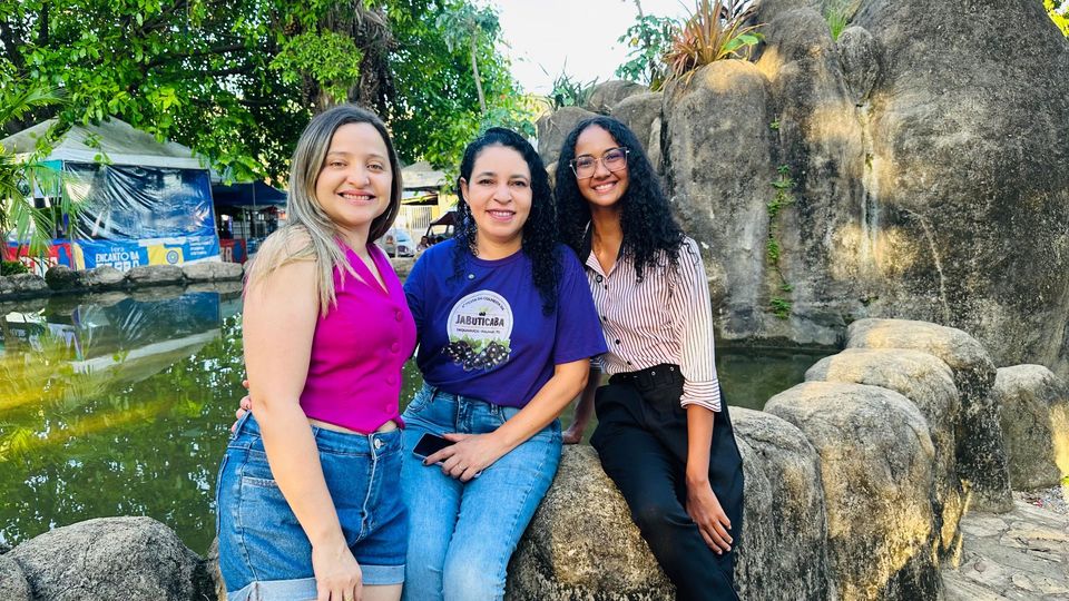 Três mulheres pousadas em frente a uma cascata 